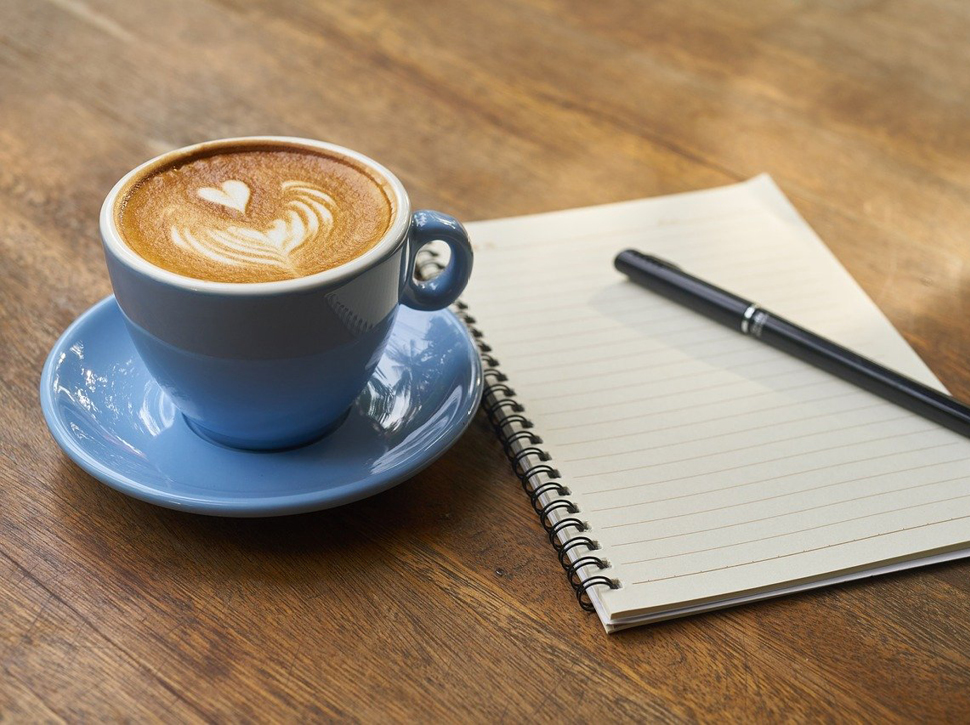 Kaffee und Schreibblock auf Holztisch
